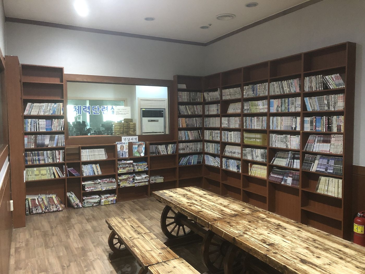 Góc nghỉ với kệ truyện và bàn gỗ trong một jjimjilbang mở 24 giờ